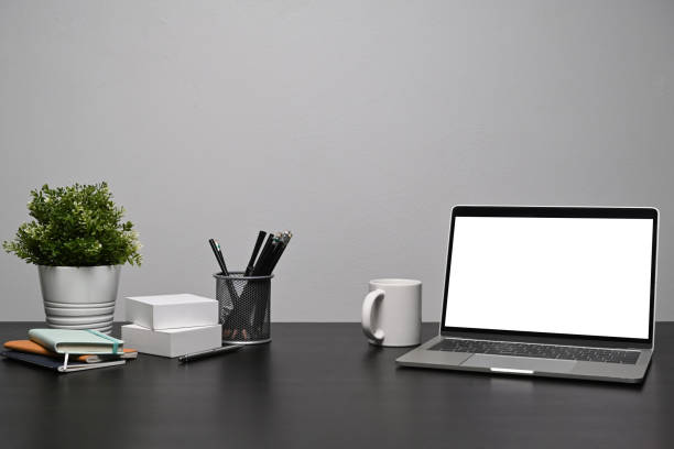 istock Computer laptop with blank display, coffee cup and supplies on black table. 1348175537
