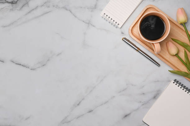 istock Top view cup of coffee, notepad and pink tulips on marble table. 1348175555