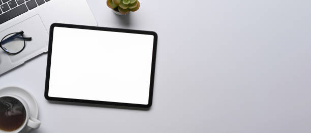 istock Top view digital tablet, laptop computer and coffee cup on white table. 1348175556