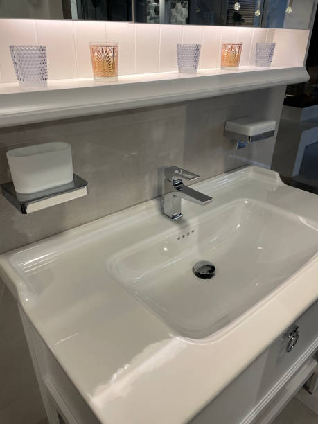 istock Image of luxury bathroom suite with large, white ceramic rectangular sink with chrome, monobloc single lever mixer tap, wall mounted soap dish, display shelf with glasses under wall mirror, marble effect wall and floor tiles 1348183027