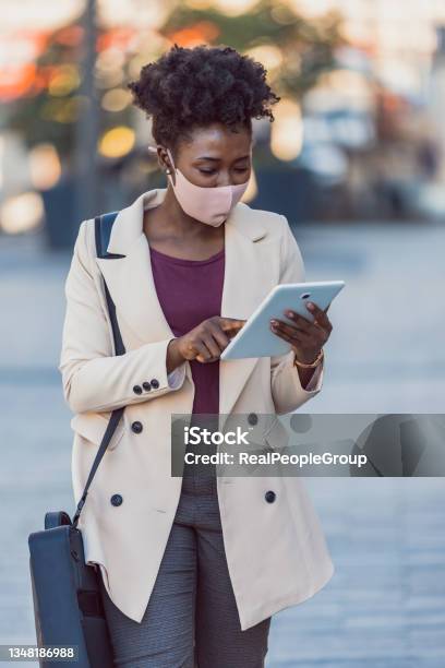 Young Black Woman In A Protective Face Mask Working On The Street Using A Tablet Pc Stock Photo - Download Image Now