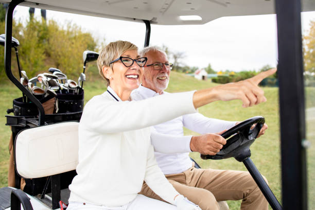 portrait d’un couple de personnes âgées en bonne santé et actif conduisant une voiture de golf et profitant de son temps libre à l’extérieur. - freedom tire swing tire swing photos et images de collection