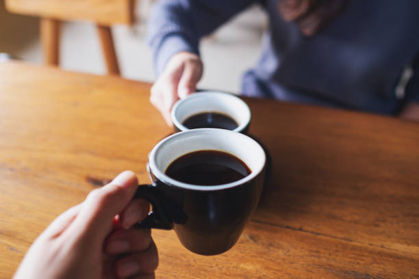 istock a man and a woman clinking coffee mugs in cafe 1348192991
