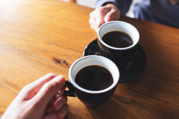 istock a man and a woman clinking coffee mugs in cafe 1348193023
