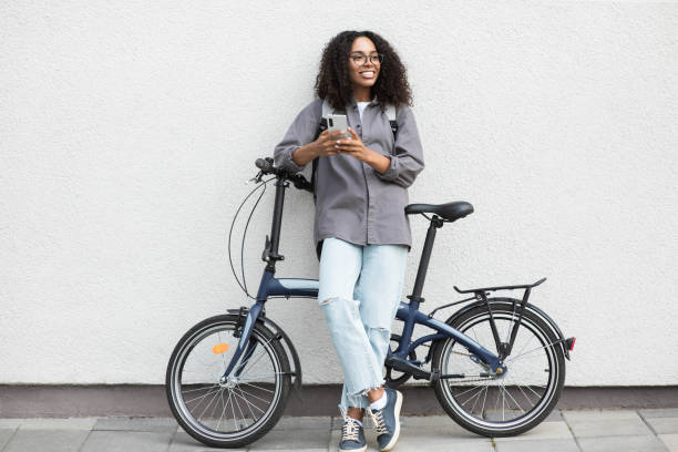istock Happy woman with bicycle using smart phone in a city 1348196336