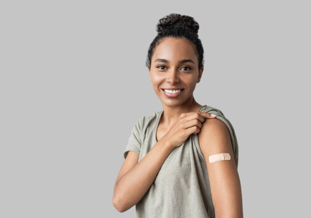 portrait of a young woman with plaster on her arm after getting a vaccine. - injetar imagens e fotografias de stock