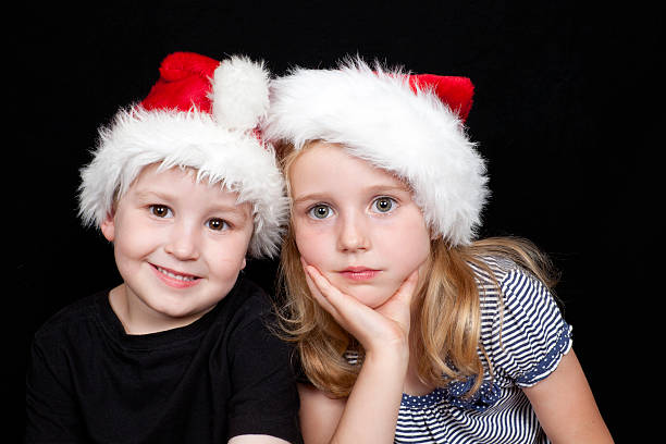 Two siblings at christmas wearing santa hats stock photo