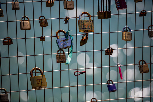 Close up of old tape wrapped massive padlock on iron chain on metal gate, property and path in blurred background, selective focus