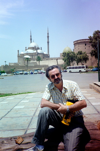 Tourist with a video recorder at the front of the Mohamed Ali Mosque and the Citadel of Cairo.\nPlease note that the image was scanned from an over thirty years old negative.