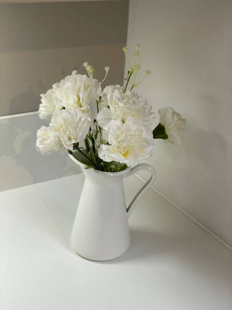 istock Full frame image of white, jug vase with artificial silk flowers on white kitchen countertop in contemporary kitchen 1348205742