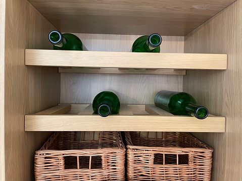 Stock photo showing a luxury kitchen with a wooden wine rack with wine bottles and wicker basket storage containers.