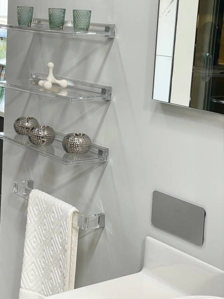 Image of luxury bathroom suite with large, white ceramic rectangular sink, wall mounted towel rail under glass floating shelves displaying glasses, wall mirror,