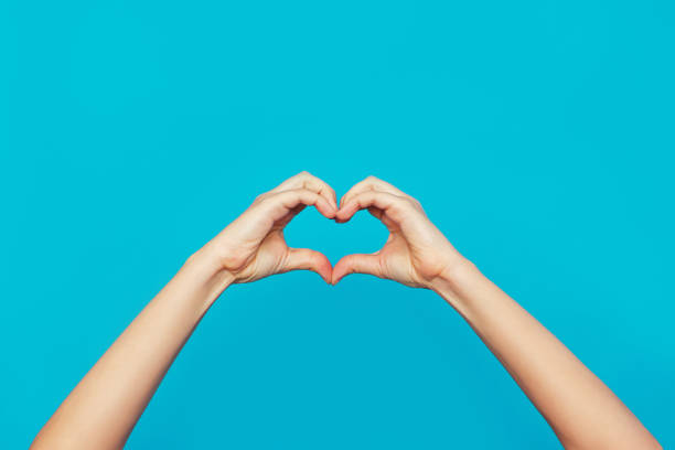 istock Female hands showing a heart shape isolated on a bright color blue background 1348207950