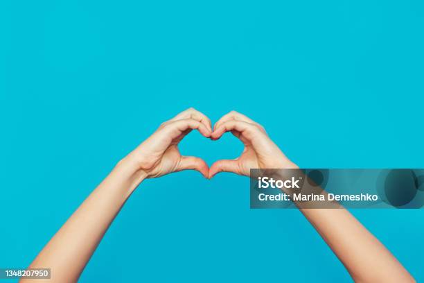 Female Hands Showing A Heart Shape Isolated On A Bright Color Blue Background Stock Photo - Download Image Now