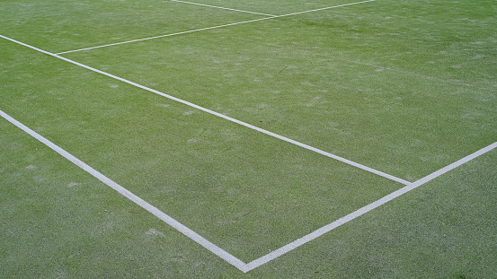 detail of synthetic tennis court. white lines on green