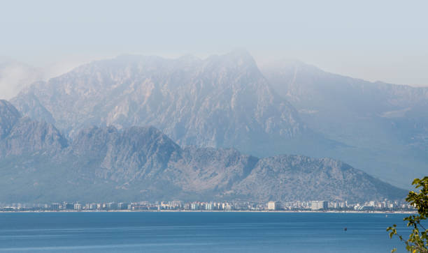 city sea and mountain view. Antalya taurus mountains sea and city view.\nMountain silhouette in foggy weather