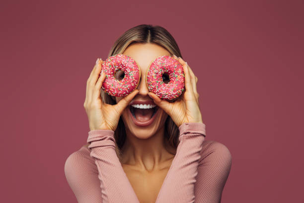 istock Young beautiful woman holding pink donuts 1348212316