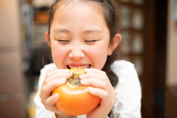 istock Girl with a big persimmon 1348213821