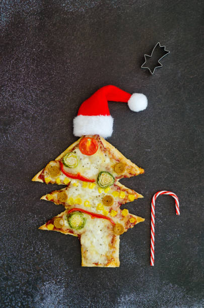 istock Delicious vegetarian Christmas tree pizza with tomatoes, cheese, vegetables on black background. Creative, funny food concept for kids. Top view, flat lay. Copy space. 1348214601