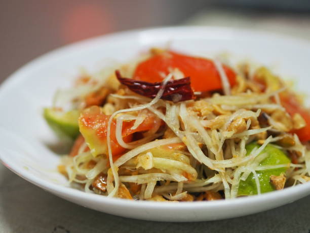 grüner papayasalat mit tomaten-chili und knoblauch, garnelen hinzufügen mit gemüse auf dem tisch servieren, thailändisches essen sauer süß scharf salzig schmecken - sour taste green traditional culture lemon stock-fotos und bilder