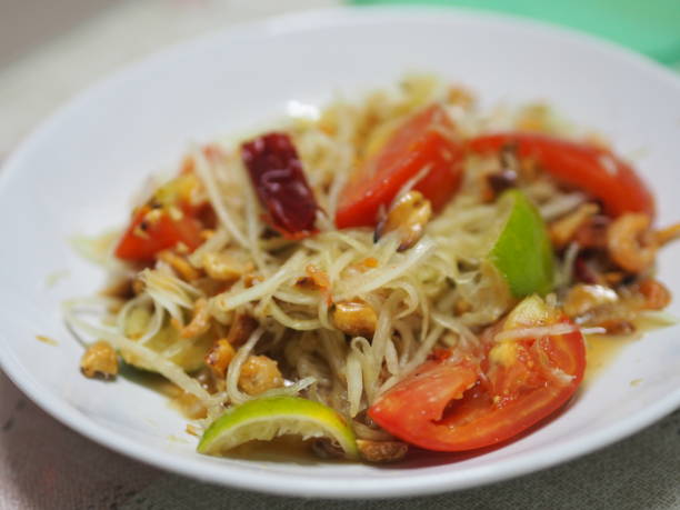 grüner papayasalat mit tomaten-chili und knoblauch, garnelen hinzufügen mit gemüse auf dem tisch servieren, thailändisches essen sauer süß scharf salzig schmecken - sour taste green traditional culture lemon stock-fotos und bilder