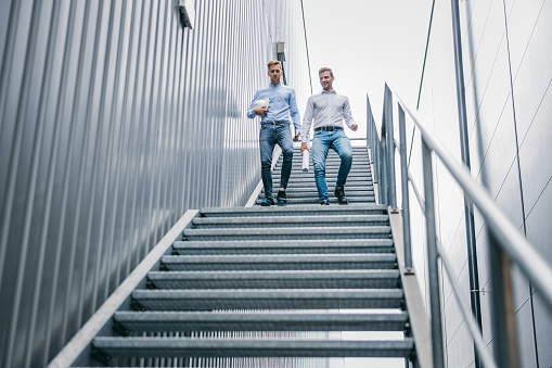 Two engineers walking downstairs of staircase at factory
