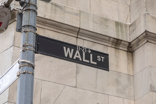 New York, USA - October 5, 2017: Wall street sign in lower  Manhattan with history of New York stock exchange and man in black.