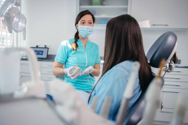 istock Young dentist showing dentures to female patient 1348218539