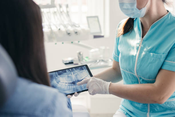 Close up of Dentist showing dental x-ray to patient Close up of Dentist showing dental x-ray to patient at dentist's office tablet pc and digital hospital tools stock pictures, royalty-free photos & images