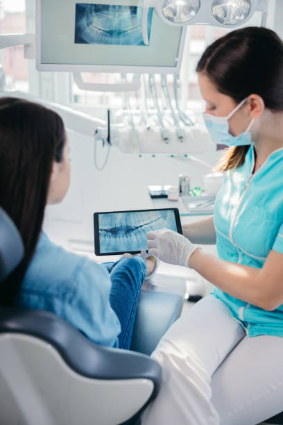 Female dentist showing dental x-ray to female patient Female dentist showing dental x-ray to female patient at dentist's office. tablet pc and digital hospital tools stock pictures, royalty-free photos & images