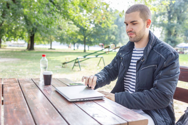 istock Young man opening laptop when resting outdoors 1348223887