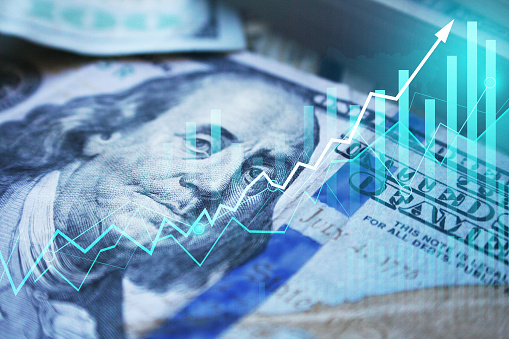 Percentage sign on top of coin stacks before blue financial graph. Horizontal composition with copy space. Business and finance concept.