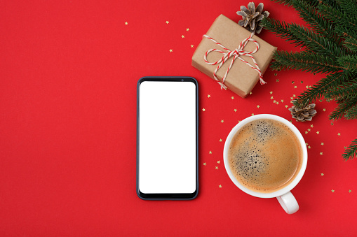 Modern smartphone with mockup on red background with christmas decoration. Flat lay template