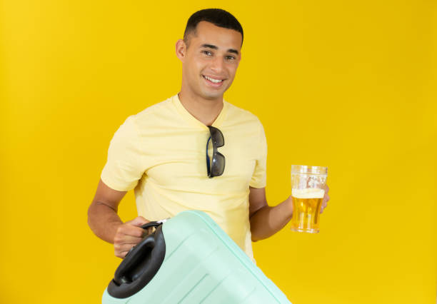 istock Young handsome man holding a suitcase and drinking beer. Holiday concept. 1348231763