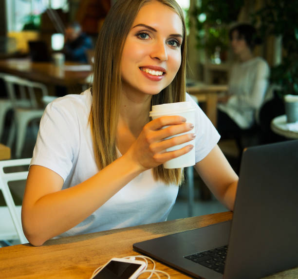 istock Happy young woman drinking coffee/tea and using laptop 1348231791