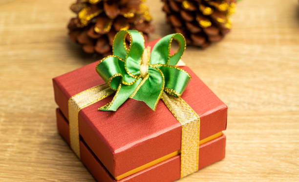 istock Christmas red gift boxes and green ribbon with tag paper lay on the table, front view with copy space. 1348233675