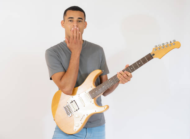 istock Handsome young man playing electric guitar isolated over white background. 1348235274