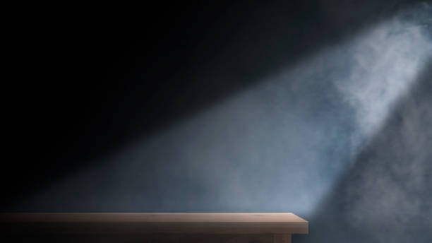 istock Brown wooden table with smoke float upon the dark abstract cement wall and studio room 1348238986