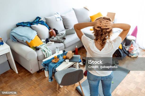 Housewife At Modern Home On Sunny Day Looking At Dirty Room Stock Photo - Download Image Now
