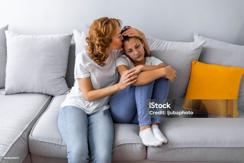 Caring mother calming and hugging upset little daughter Mother Talking With Unhappy Teenage Daughter On Sofa Teenager Stock Photo