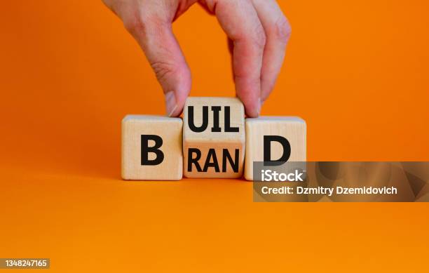 Build Your Brand Symbol Businessman Turns Wooden Cubes And Changes The Word Build To Brand Beautiful Orange Background Build Your Brand And Business Concept Copy Space Stock Photo - Download Image Now