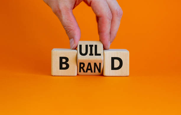 build your brand symbol. businessman turns wooden cubes and changes the word 'build' to 'brand'. beautiful orange background. build your brand and business concept. copy space. - branding imagens e fotografias de stock