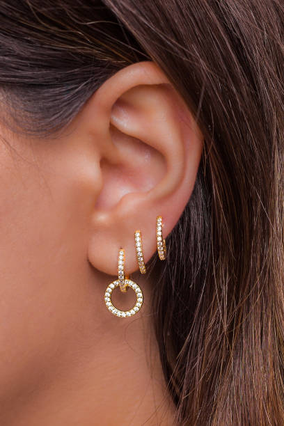 Woman ear with mulriple piercings wearing beautiful earrings with zirconia Woman ear with mulriple piercings wearing beautiful earrings with zirconia- details capture artists model stock pictures, royalty-free photos & images