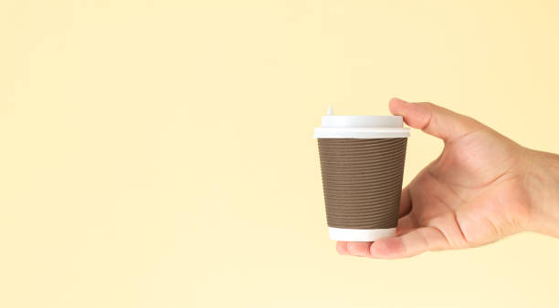 istock Man hand holding paper coffee cup with white plastic cap 1348248697
