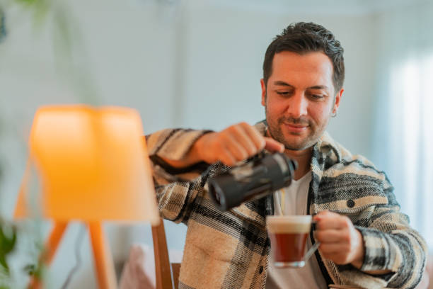 istock Man pouring coffee while working on laptop at home 1348249318