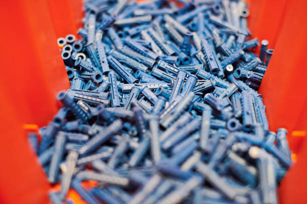 Dowels wall plugs close up. Plastic blue dowels on red background, dowels for fixation and installation and various wall materials, concrete and wood. Accessories for repairing and handymen