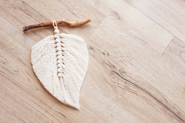 istock Macrame leaf  in natural color and thread windings lying on a wooden table. Cotton rope decor macrame to make your room more cozy and unique. Woman hobby. Handmade wall hanging decor. Copy space 1348252304