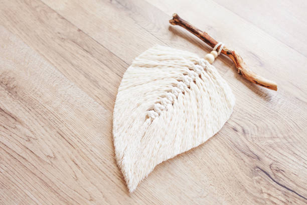 istock Macrame leaf  in natural color and thread windings lying on a wooden table. Cotton rope decor macrame to make your room more cozy and unique. Woman hobby. Handmade wall hanging decor. Copy space. 1348252355
