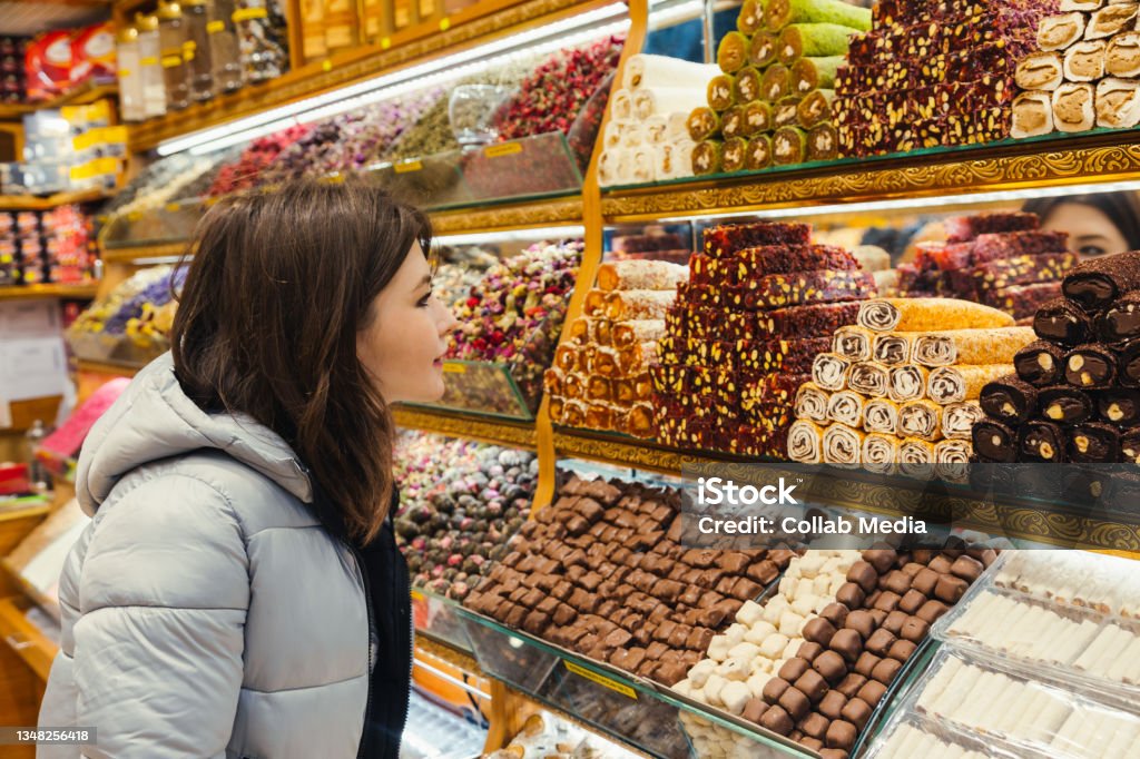 Young woman looking at Turkish delight, various lokum, colorful sweets and chocolate at store selling delight Market - Retail Space Stock Photo
