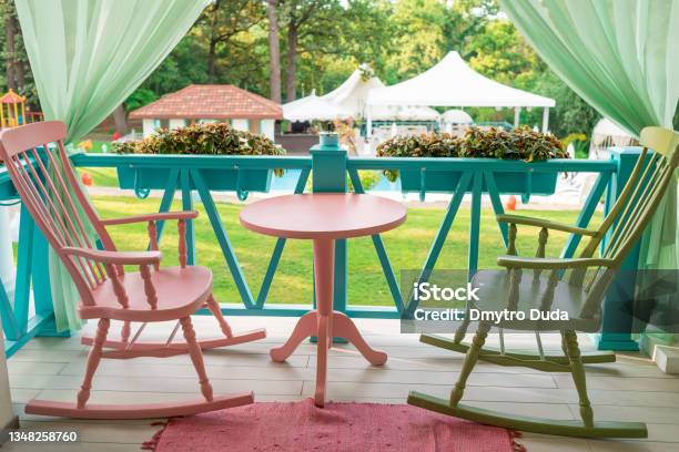 Pink And Green Wooden Rocking Chairs And Table On Porch Or Balcony Two Relaxing Armchairs On Porch Of Luxury Hotel Empty Cafe With Rocking Chairs And Table On Summer Terrace Outdoor Free Space Stock Photo - Download Image Now